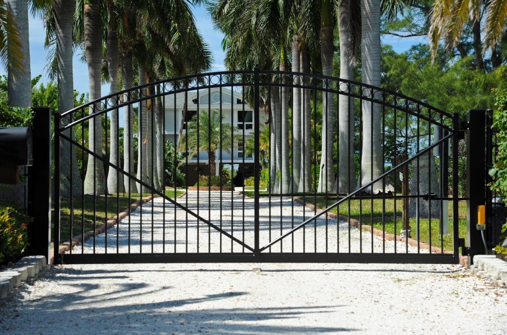 Iron Security Gates Protecting the Entrance to a Palm Tree Lined Driveway